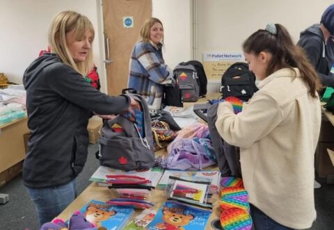 Group of ladies packing items such as pyjamas, toiletries into a bag pack for children who enter emergency care