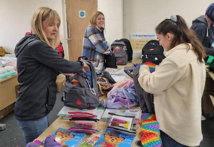 Group of ladies packing items such as pyjamas, toiletries into a bag pack for children who enter emergency care